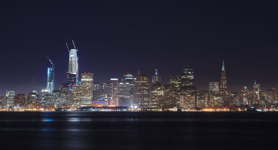 San Francisco skyline at night, downtown towers reflected over the bay